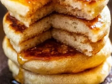 Plate of delicious homemade mini pancakes topped with syrup and berries.