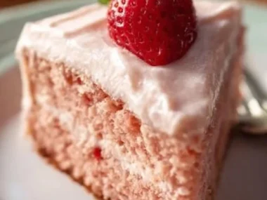 A slice of homemade strawberry cake topped with fresh strawberries and cream