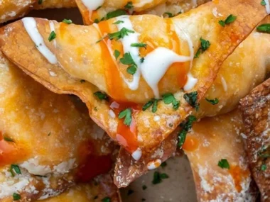 Crispy air fryer buffalo chicken wontons served on a plate, garnished with sauce.