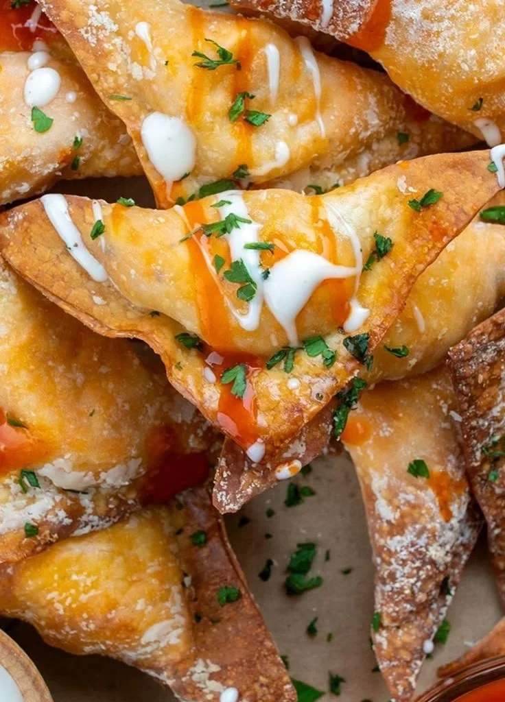 Crispy air fryer buffalo chicken wontons served on a plate, garnished with sauce.