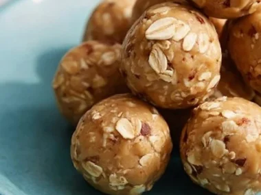 A close-up of Peanut Butter Energy Balls on a wooden table, showcasing their texture.