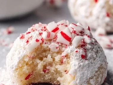 Frosted Peppermint Snowball Cookies on a plate, decorated with festive sprinkles.