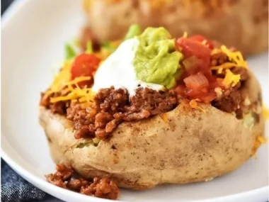 Delicious Taco Potatoes topped with cheese, garnished with fresh herbs and salsa
