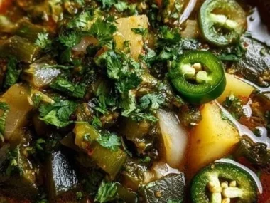 Bowl of cozy roasted poblano soup garnished with cilantro and cream