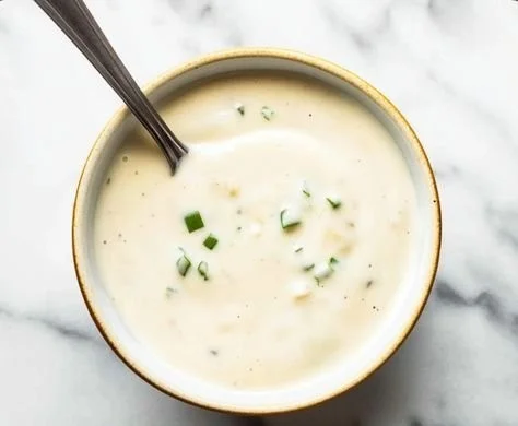 Creamy horseradish sauce served in a bowl with a garnish of fresh herbs.