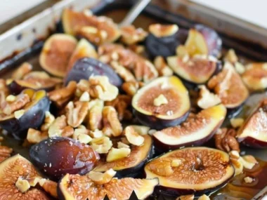 Delicious honey-roasted walnuts and figs presented on a wooden board.
