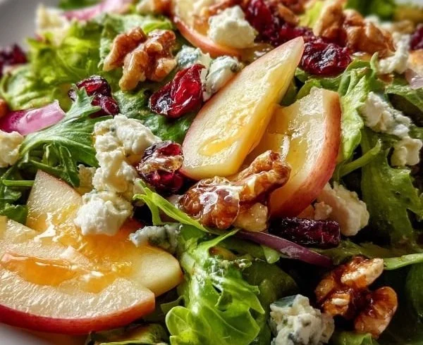 Honeycrisp apple salad with feta, nuts, and fresh greens served on a plate.