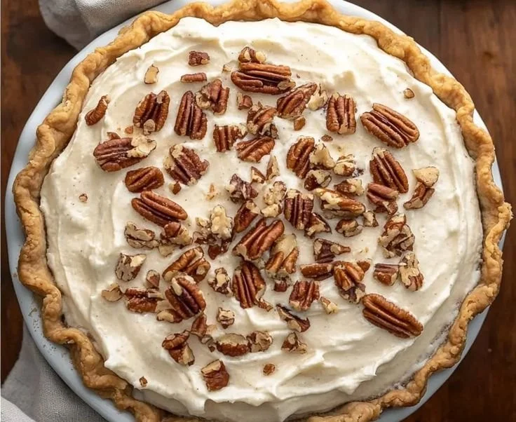 Irresistibly creamy pecan cream pie topped with pecans and whipped cream