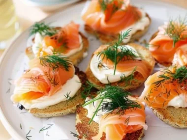 A delicious smoked salmon and dill blini cake topped with fresh herbs.
