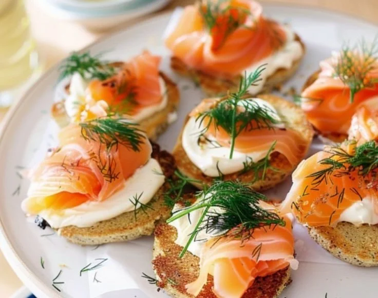A delicious smoked salmon and dill blini cake topped with fresh herbs.