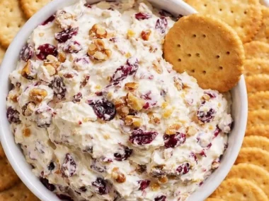 Cranberry Walnut Cream Cheese Dip served in a bowl with crackers and fruits.