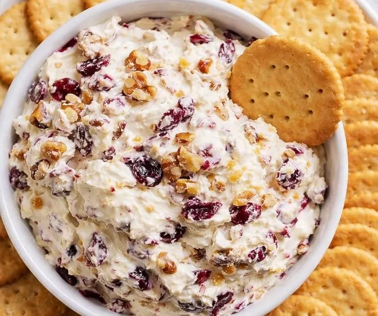 Cranberry Walnut Cream Cheese Dip served in a bowl with crackers and fruits.