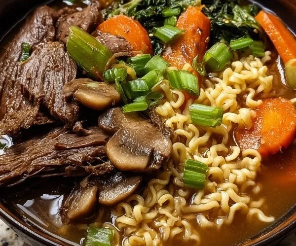 Bowl of slow cooker beef ramen noodles garnished with vegetables