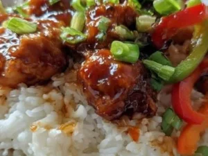 Delicious sticky chicken rice bowl topped with fresh vegetables and sauce