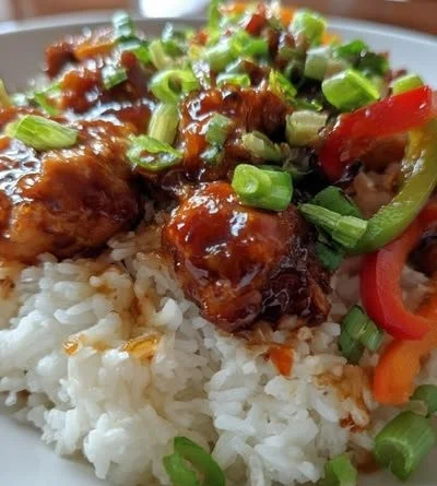 Delicious sticky chicken rice bowl topped with fresh vegetables and sauce
