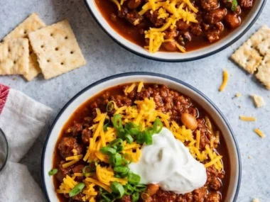 Bowl of the best chili recipe topped with cheese and herbs