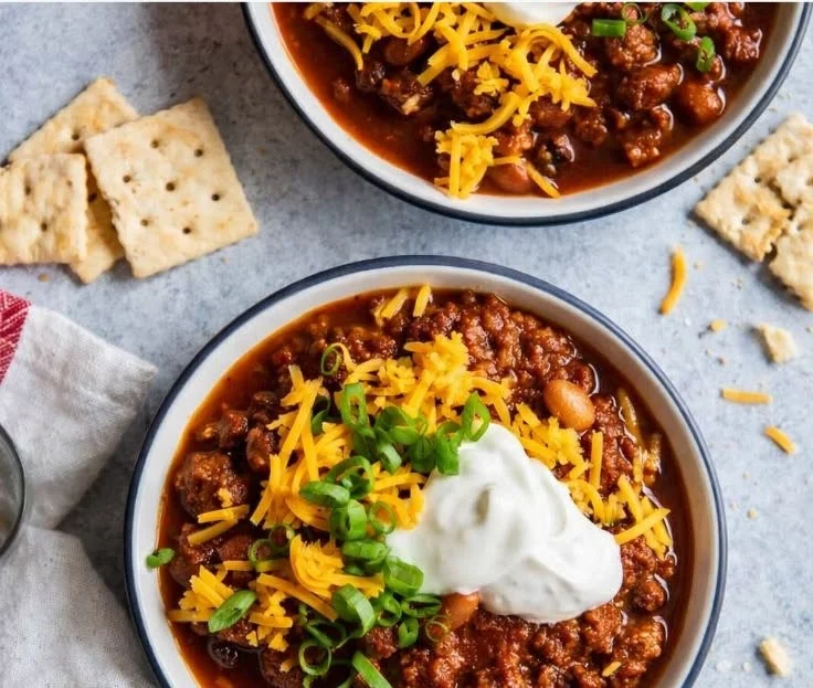 Bowl of the best chili recipe topped with cheese and herbs