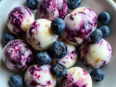 Blueberry swirl yogurt bites surrounded by fresh blueberries and yogurt