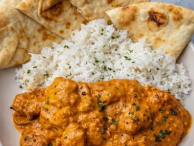 Delicious butter chicken served with rice and naan bread