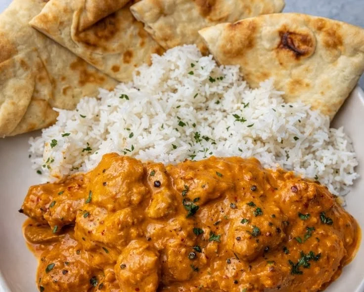 Delicious butter chicken served with rice and naan bread