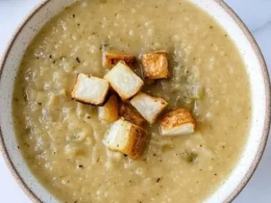 Bowl of creamy Cauliflower Potato Leek Soup garnished with herbs.