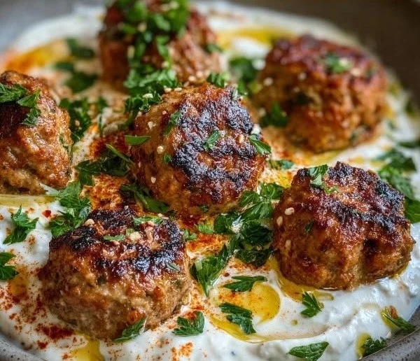 Plate of Chicken Kofta with garlic yogurt sauce garnished with herbs