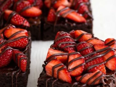 Delicious chocolate-covered strawberry brownies topped with fresh strawberries.
