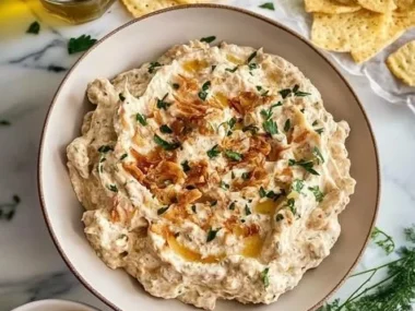 Creamy caramelized onion dip served in a bowl with chips.