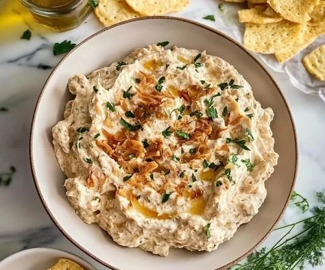 Creamy caramelized onion dip served in a bowl with chips.