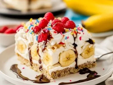 Fluffy banana split cake with layers of banana, whipped cream, and chocolate drizzle