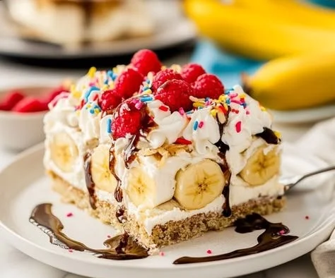 Fluffy banana split cake with layers of banana, whipped cream, and chocolate drizzle