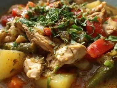 Bowl of Green Chile Chicken Stew garnished with fresh herbs and chilies