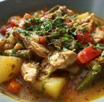 Bowl of Green Chile Chicken Stew garnished with fresh herbs and chilies