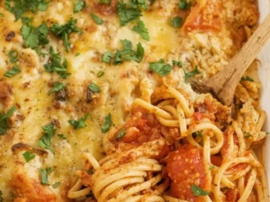 High protein baked spaghetti casserole topped with cheese and herbs