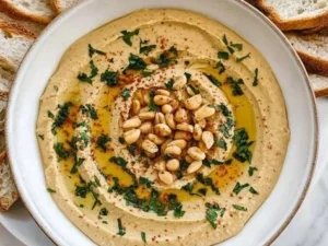 Bowl of peanut butter hummus served with fresh veggie sticks.