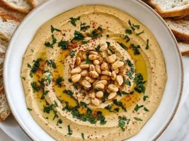 Bowl of peanut butter hummus served with fresh veggie sticks.