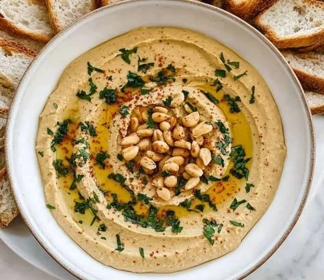Bowl of peanut butter hummus served with fresh veggie sticks.