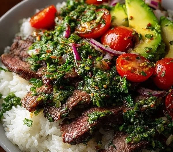 Skirt steak rice bowl drizzled with chimichurri sauce on a wooden table